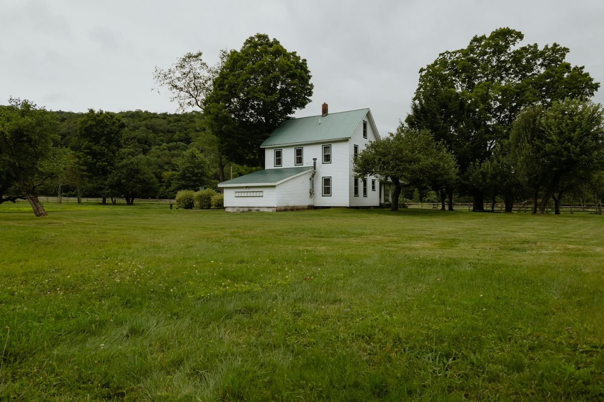 White farmhouse with a large lawn in rural New York